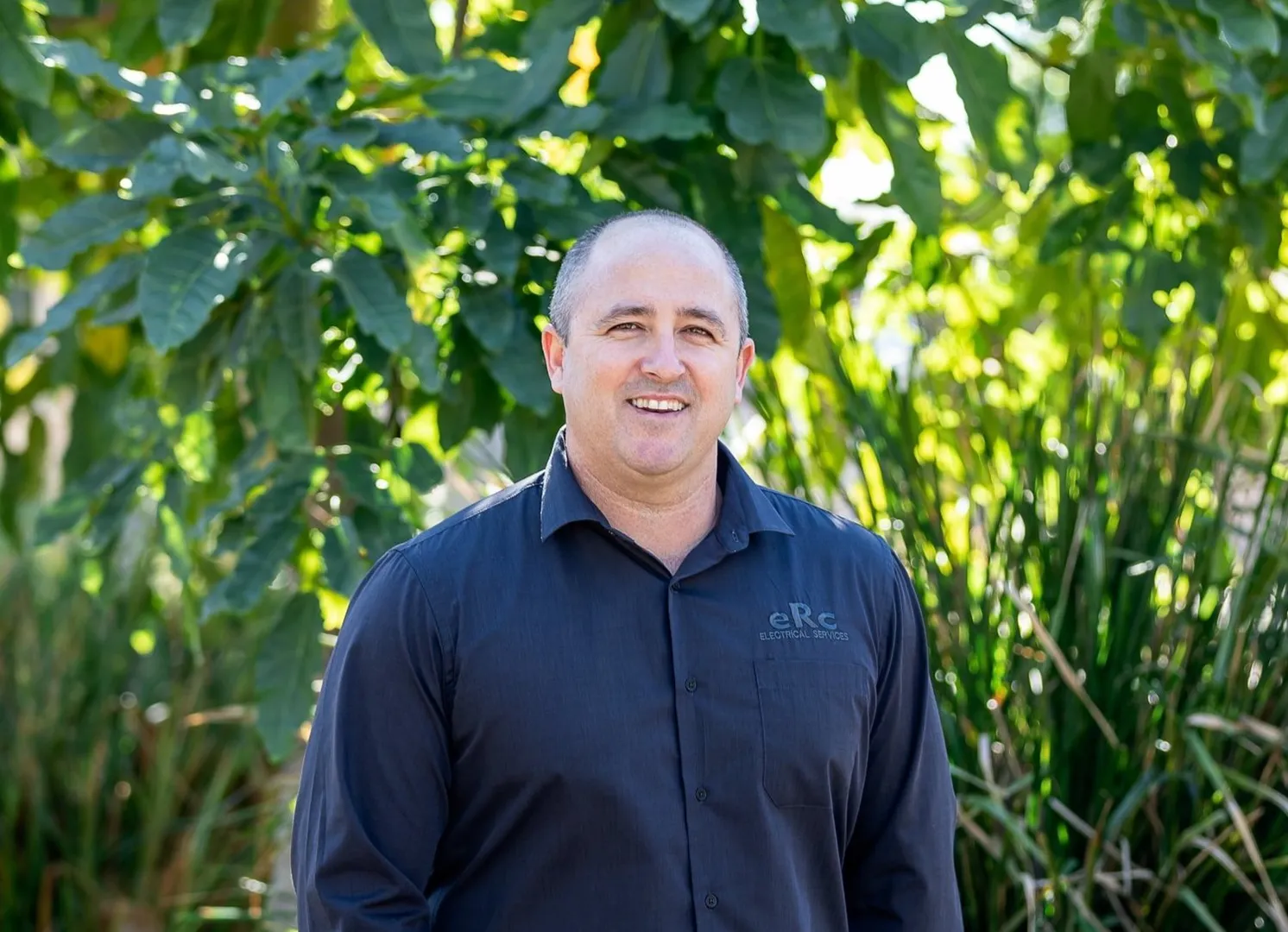 Smiling man in black shirt outdoors.